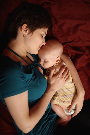 Mom and baby are asleep, embracing each other. View from aboveの写真素材