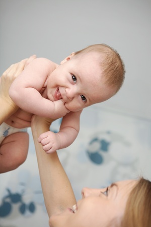 Mother raised her baby to the ceiling. The boy smiles and looks into the camera.の写真素材
