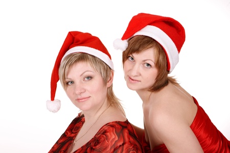 Two women in Christmas hats and red clothes. They looked into the camera. Close-up.の写真素材