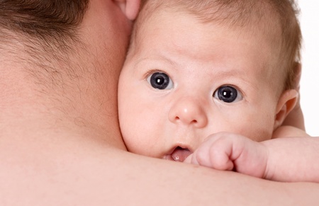 /little girl looks out from his father's shoulder