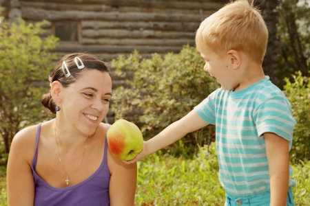 	The little boy holds out an apple mom  Summer day outdoorsの写真素材