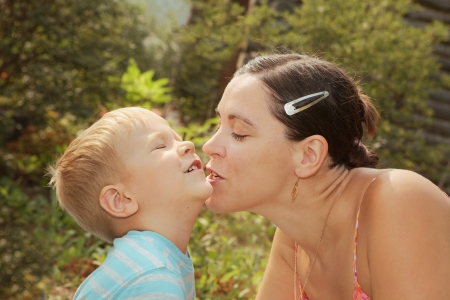 Woman kiss little son in the chin  Summer day, outdoorsの写真素材