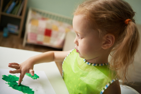 Girl draws a finger paints something greenの写真素材
