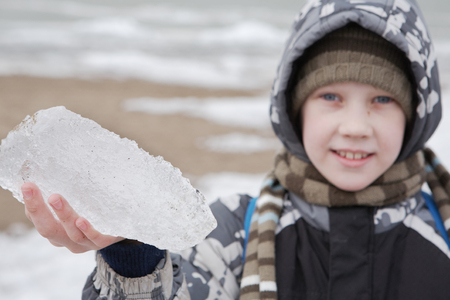 The boy is holding a piece of ice and smilingの写真素材