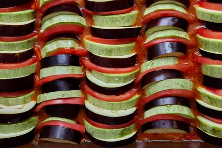 Slices of zucchini, eggplant and tomato are in a sauce of stewed vegetablesの写真素材