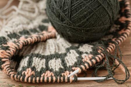 on wooden table is an unfinished knitwear made of wool yarnの写真素材