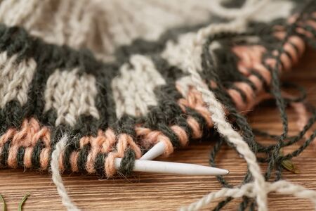 on wooden table is an unfinished knitwear made of wool yarn
