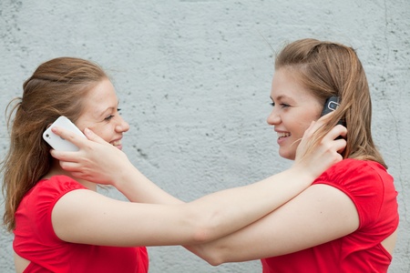 Twin girls in red with phonesの写真素材