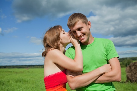 girl is whispering in the ear of the guy