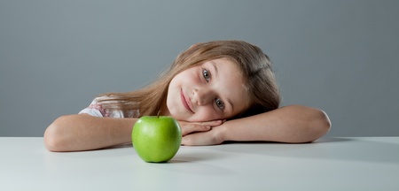 girl at the table with a green appleの写真素材