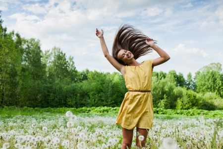 young girl among dandelions summer dayの写真素材