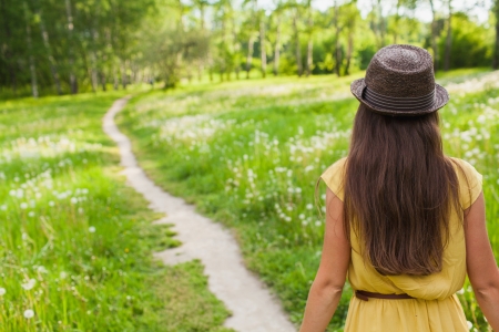 Young girl walking on a footpath among meadowsの写真素材