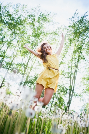 young girl among dandelions summer dayの写真素材