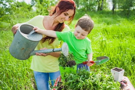 Mom and son watering from a watering canの写真素材