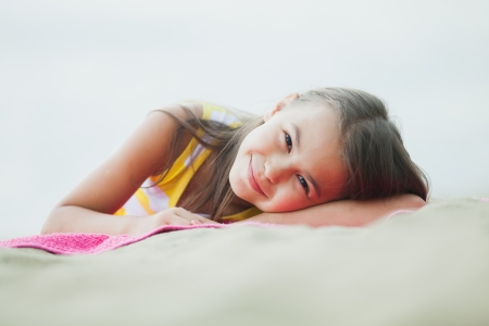 five-year-old girl lying on the beachの写真素材