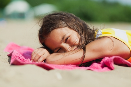 five-year-old girl lying on the beachの写真素材