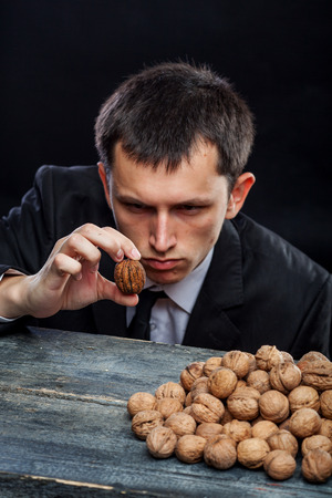 young man looking at a nut selected from a pile of nutsの写真素材