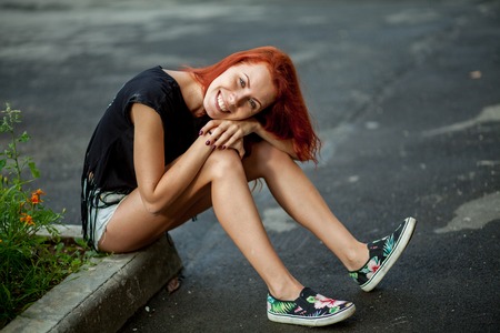 Young beautiful woman sits on rock borderの写真素材