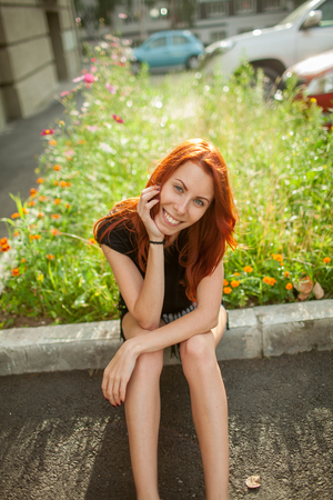 Young beautiful woman sits on rock borderの写真素材