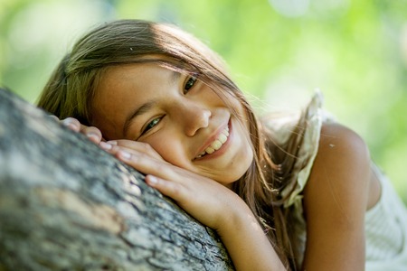 Happy young girl sitting in a treeの写真素材