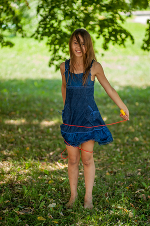 girl in blue dress jumping rope and smilingの写真素材