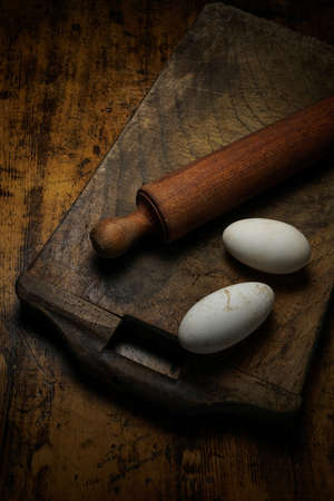 Mortara 09/10/2019: old wooden cutting board with rolling pin and goose eggsの写真素材