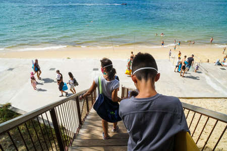 La Teste-de-Buch - 08/25/2020: a boy with skimboard descending a wooden walkaway to the seaのeditorial素材