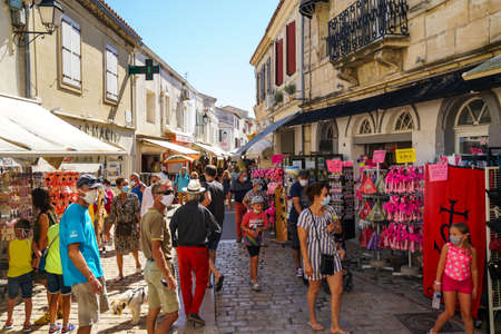 Saintes Maries de la Mer - 09/04/2020: Saintes Maries de la Mer - 09/04/2020: people with mask protections walk in the street among souvenirs shopsのeditorial素材