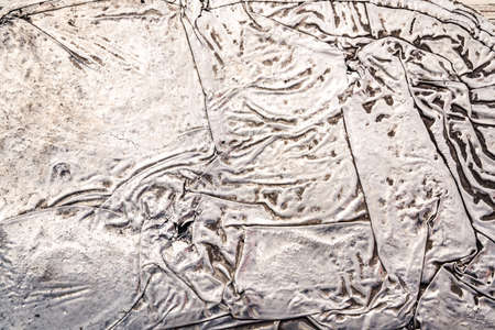 wrinkled sheet of crushed tin aluminum silver foil backgroundの写真素材