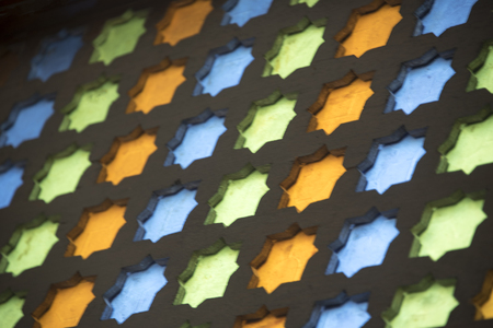 Essaouria, Morocco - September 2017: Screen made from colourful blue, green and yellow gold glass in traditional geometric patterns set in an antique wooden frame - close upのeditorial素材