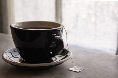 USA, Boston - January 2018 - Hot cup of tea on a marble window sill in front of an Ice coated glass window paneの写真素材