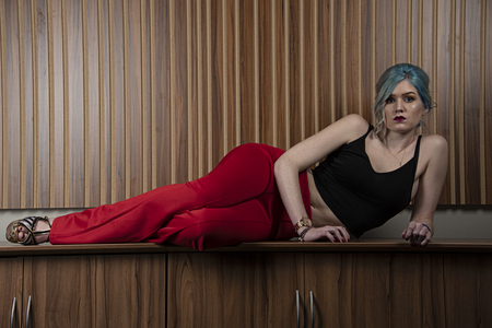 BIRMINGHAM,UK - FEBRUARY 2018: Caucasian female model, Age 22, Blue dyed hair, Red lips, black strappy top, red trousers, full bodyのeditorial素材