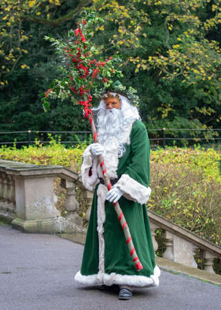 UK, Market Bosworth, Victorian Christmas Fair - December 2015: Father Christmas robed in green, masked and carrying holly branchesのeditorial素材