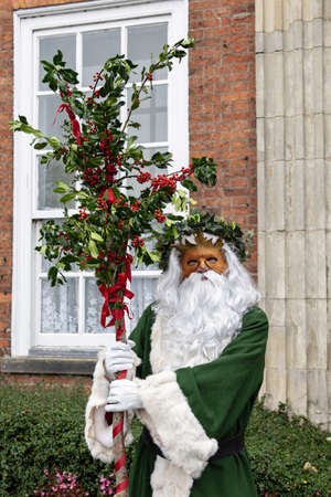 UK, Market Bosworth, Victorian Christmas Fair - December 2015: Father Christmas robed in green, masked and carrying holly branches,のeditorial素材
