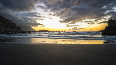 Tenerife, June 2022: A rock strewn bay at sunset with the tide rolling inの写真素材