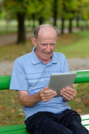 Friendly handsome old man with tablet computer の写真素材
