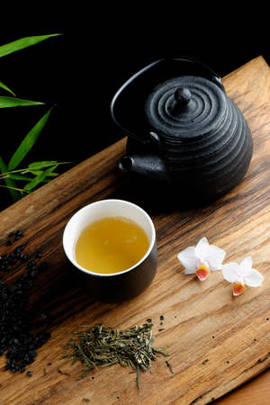 Asian tea set on bamboo mat, green tea, orchid and volcano sandの写真素材
