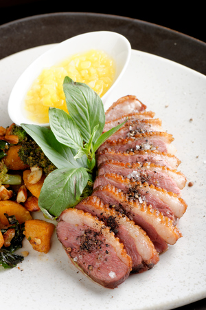 Duck breasts with sour mango sauce and pan-seared sweet potatoes, broccoli and almondsの写真素材