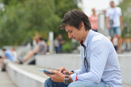 Young student reading on tablet computer in the cityの写真素材