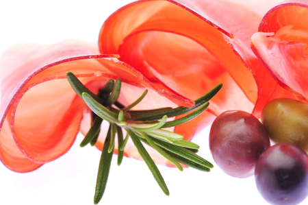 Sliced prosciutto with rosemary and olives on white backgroundの写真素材
