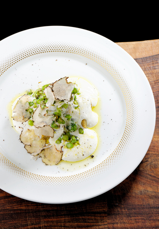 Slices of tasty corn polenta with truffles mushrooms, asparagus, cheese and vegetables on a white plate on the tableの写真素材