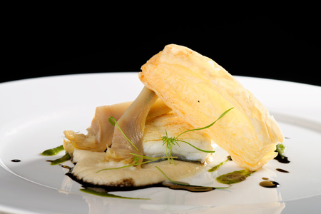 Fine dining, baked cod fillet with spinach sauce and roasted onions