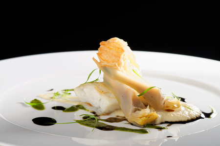 Fine dining, baked cod fillet with spinach sauce and roasted onions