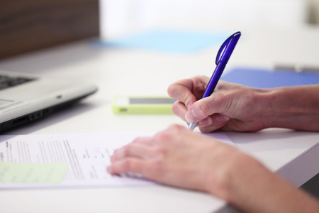 hands writing with pen in office