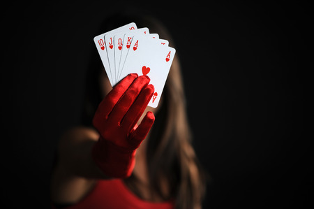 female hand with royal flush on black bacground