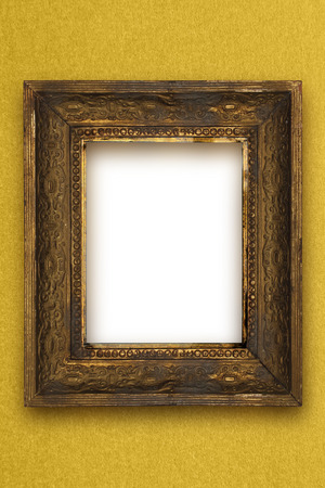 classic old wooden picture frame carved by hand on gold wallpaper backgroundの写真素材