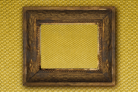 classic old wooden picture frame carved by hand on gold wallpaper backgroundの写真素材