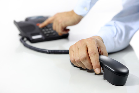 hands with office phone on deskの写真素材