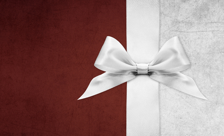 Shiny silver satin ribbon bow on red backgroundの写真素材
