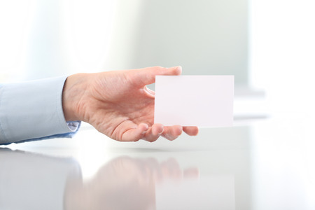 Hand hold blank business card, on desk topの写真素材